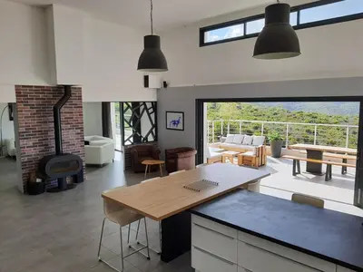a kitchen and living room with a table and a fireplace at Superbe villa moderne sur Capo di Muro in Coti-Chiavari