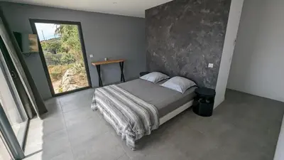 a bedroom with a bed with a large window at Superbe villa moderne sur Capo di Muro in Coti-Chiavari