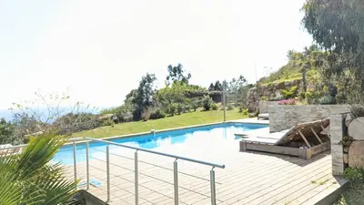 a swimming pool in a yard with a wooden deck at Superbe villa moderne sur Capo di Muro in Coti-Chiavari