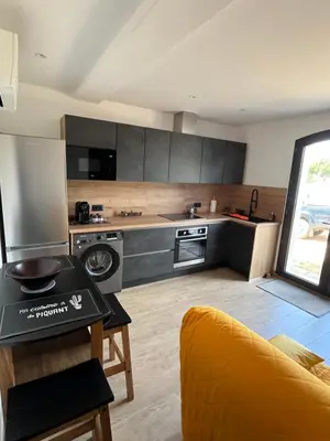 a kitchen with stainless steel appliances and a yellow couch at Appartement T2 Porticcio in Porticcio