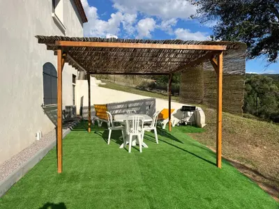 a pergola with a table and chairs on grass at Appartement T2 Porticcio in Porticcio