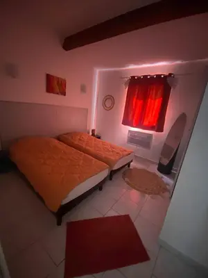 a bedroom with two beds and a window with red curtains at Maison T3 in Piana