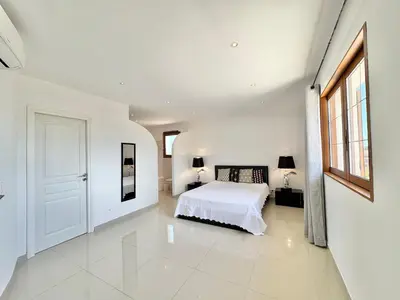 a white bedroom with a bed and a window at Villa avec piscine à Lecci in Lecci