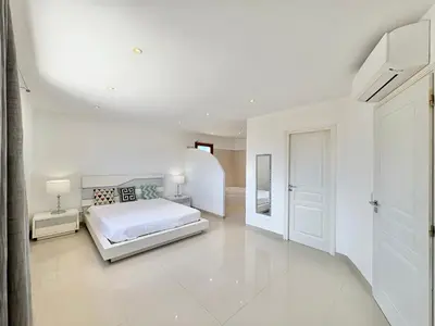 a white bedroom with a bed and a hallway at Villa avec piscine à Lecci in Lecci