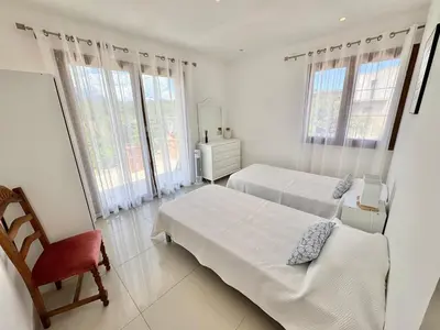 a bedroom with two beds and a chair and windows at Villa avec piscine à Lecci in Lecci