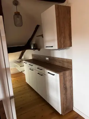 a kitchen with white cabinets and a wooden floor at Charming apartment in Corsican Village in Vescovato