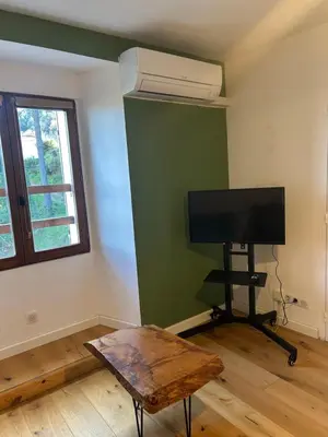 a living room with a tv and a table and a window at Charming apartment in Corsican Village in Vescovato