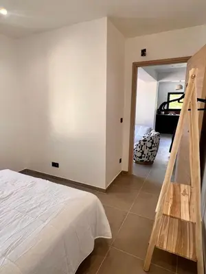 a bedroom with a white bed and a staircase at Maison Di Fiori, location neuve avec piscine in Porto-Vecchio