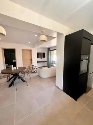 a kitchen and living room with a table and a couch at Maison Di Fiori, location neuve avec piscine in Porto-Vecchio