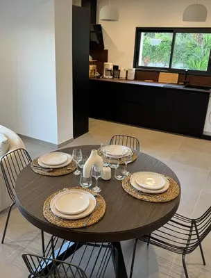 a dining room table with plates and wine glasses on it at Maison Di Fiori, location neuve avec piscine in Porto-Vecchio