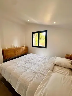 a bedroom with a large white bed and a window at Maison Di Fiori, location neuve avec piscine in Porto-Vecchio