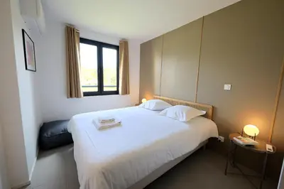 a bedroom with a large white bed with a window at U Bellu Paradisu - T3 vue mer, piscine, plage privé in Pianottoli-Caldarello