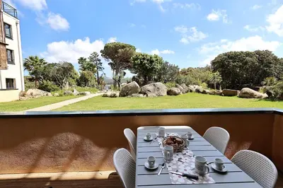 a table on a balcony with a view of a yard at U Bellu Paradisu - T3 vue mer, piscine, plage privé in Pianottoli-Caldarello