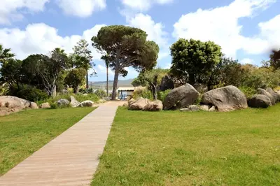 a wooden path through a park with rocks and trees at U Bellu Paradisu - T3 vue mer, piscine, plage privé in Pianottoli-Caldarello