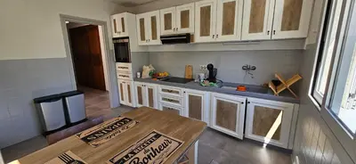 a kitchen with white cabinets and a wooden table at BELLA VISTA-Wifi-VUE MER PANORAMIQUE in Sari Solenzara