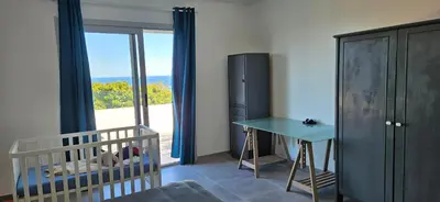 a room with a crib and a table and a window at BELLA VISTA-Wifi-VUE MER PANORAMIQUE in Sari Solenzara