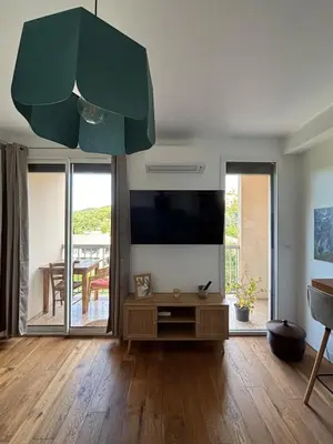 a living room with a flat screen tv and a table at Confort et modernité Ajaccio in Ajaccio