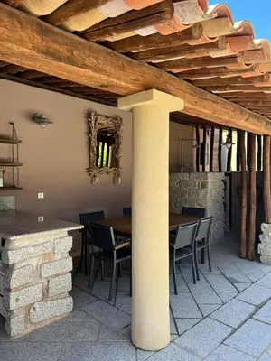 a patio with a table and chairs under a wooden ceiling at Villa Ghjulia in Porto-Vecchio
