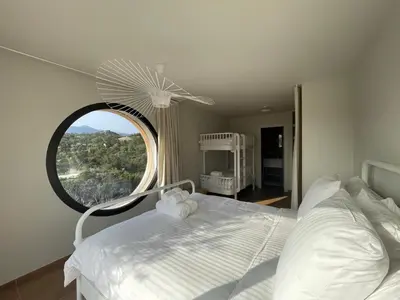a bedroom with a white bed with a large window at luxe et sérénité in Lecci