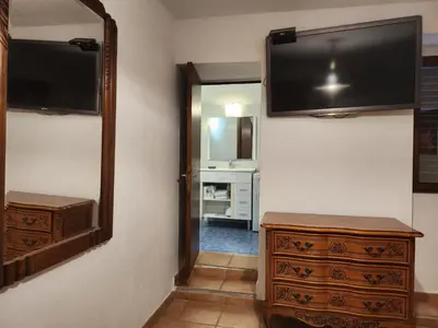 a room with a tv and a dresser and a mirror at Deux pièces tout confort Monacia d'Aullène in Monacia-dʼAullène