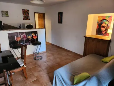a room with a bed and a table and a painting at Deux pièces tout confort Monacia d'Aullène in Monacia-dʼAullène