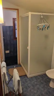 a bathroom with a glass shower door and a sink at Deux pièces tout confort Monacia d'Aullène in Monacia-dʼAullène