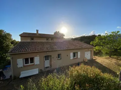 a house on a hill with the sun behind it at u caseddu in Olivese