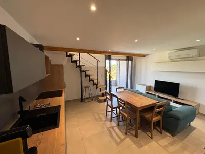 a living room with a dining room table and a staircase at LA MARANA - 1 minute des plages - Proche BASTIA AEROPORT - T2 entièrement neuf avec cuisine équipée in Lucciana