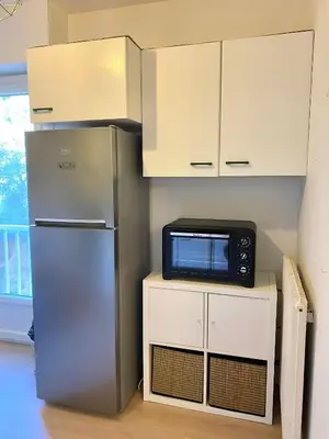 a kitchen with a table and a refrigerator at Grand studio neuf, lumineux et au calme ! Tout équipé - Ajaccio in Ajaccio