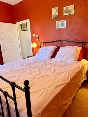 a large bed in a bedroom with a red wall at Maison traditionnelle avec vues sur St Michel in Murato