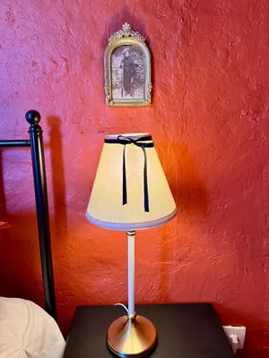 a lamp on a table next to a red wall at Maison traditionnelle avec vues sur St Michel in Murato