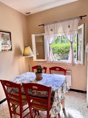 a dining room table with chairs and a table and a window at Maison traditionnelle avec vues sur St Michel in Murato