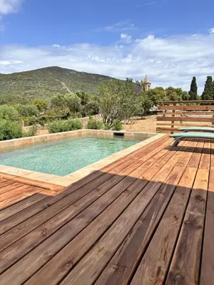a wooden deck with a pool and a bench on top of it at Sposata - maison avec piscine privée - Figari in Figari