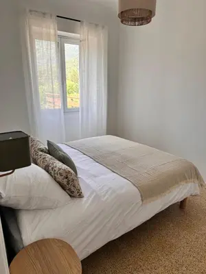 a white bedroom with a bed with pillows and a window at Sposata - maison avec piscine privée - Figari in Figari