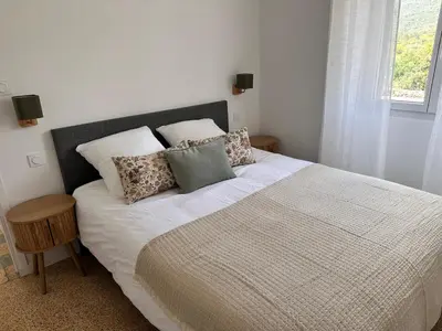 a bedroom with a large bed with pillows and a window at Sposata - maison avec piscine privée - Figari in Figari
