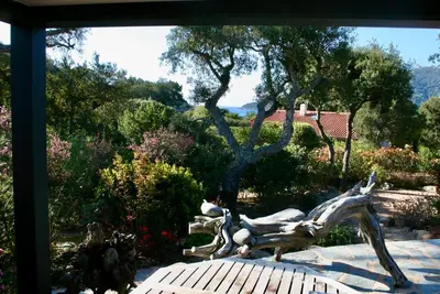 a statue sitting on a bench in a garden at Villa Tarco in Porto-Vecchio