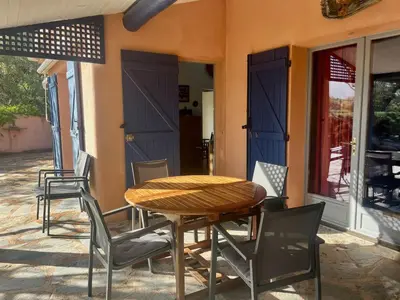 a table and chairs on a patio with blue doors at Villa Tarco in Porto-Vecchio