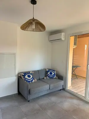 a living room with a couch and a fan at Appartement dans résidence 3 étoiles in Lecci