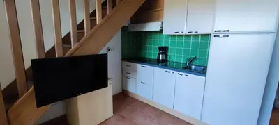a kitchen with white cabinets and a green wall at Appt 4-6 couchages climatisé avec 2 piscines et 200 m des plages et criques in Linguizzetta