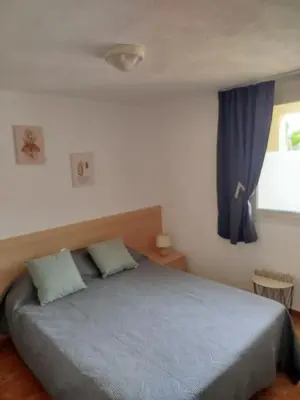 a bedroom with a bed with blue sheets and a window at Appt 4-6 couchages climatisé avec 2 piscines et 200 m des plages et criques in Linguizzetta