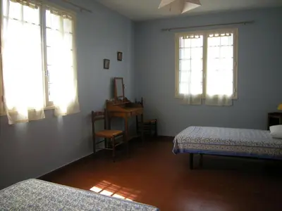 a bedroom with two beds and a desk and two windows at Appartement à Speloncato dans la plaine du Reginu 2, pour 3 personnes in Speloncato