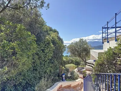 a house on a hill with a fence and trees at Casa Blue Cala Rossa with Pool in Lecci