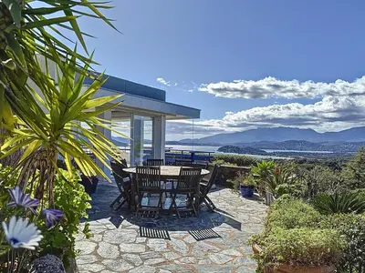 a table and chairs on a patio with a view of the ocean at Casa Blue Cala Rossa with Pool in Lecci