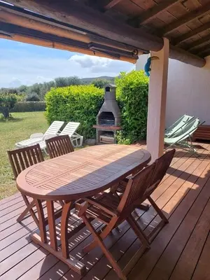 a wooden table and chairs on a deck with a grill at Maison proche Porto Vecchio in Porto-Vecchio