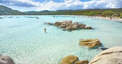 a person in the water at a beach with rocks at Maison proche Porto Vecchio in Porto-Vecchio