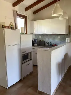 a kitchen with white appliances and white cabinets at Maison proche Porto Vecchio in Porto-Vecchio