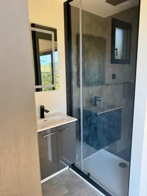 a bathroom with a glass shower and a sink at Lodge sous les oliviers in Propriano