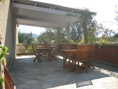 a patio with wooden tables and chairs under a pavilion at Appartement à Speloncato dans la plaine du Reginu 1, pour 3 personnes in Speloncato