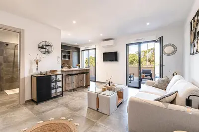 a living room with a couch and a kitchen at Les Vagues d'Agosta in Albitreccia