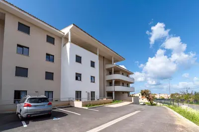 a car parked in a parking lot in front of a building at Les Vagues d'Agosta in Albitreccia